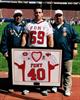 Chuck's nephew Michael holding Chuck's jersey, flanked by Chuck's father & brother.