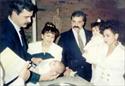 Serving as Godparents to Chuck's son Charlie are Lt. Paul Mitchell with Chuck's sister-in-law Ruth.  Chuck is holding daughter Norma Jean while wife Norma looks on.  (1989)